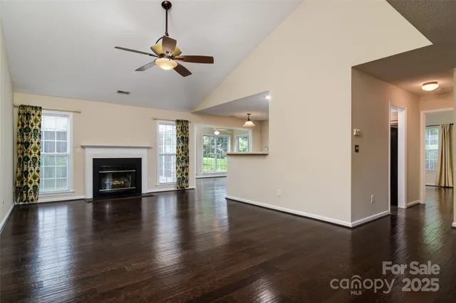 a view of a livingroom with wooden floor a ceiling fan and a kitchen