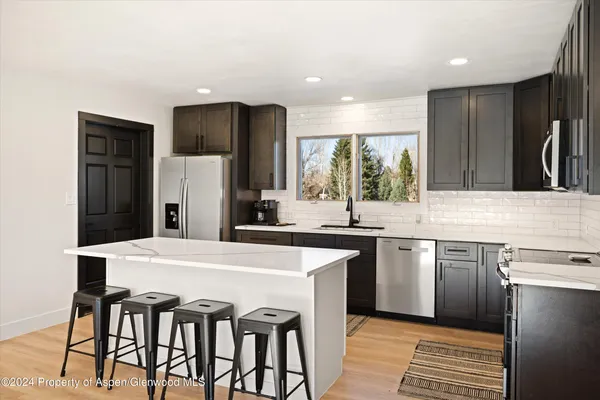 a kitchen with stainless steel appliances granite countertop a table chairs sink refrigerator and cabinets