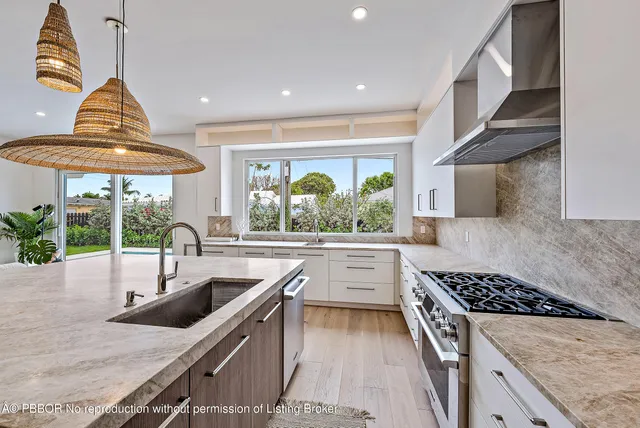 a kitchen with stainless steel appliances granite countertop a sink a counter space and a view of living room