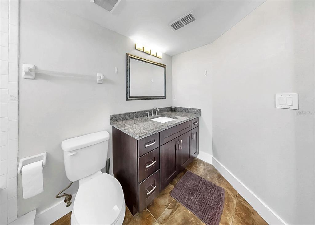 6504 Surfside Boulevard, Unit 4 Apollo Beach, FL 33572 - Photo 31 of 41 a bathroom with a granite countertop toilet sink and mirror