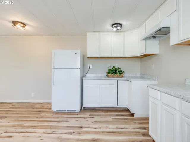 a white kitchen with sink and refrigerator