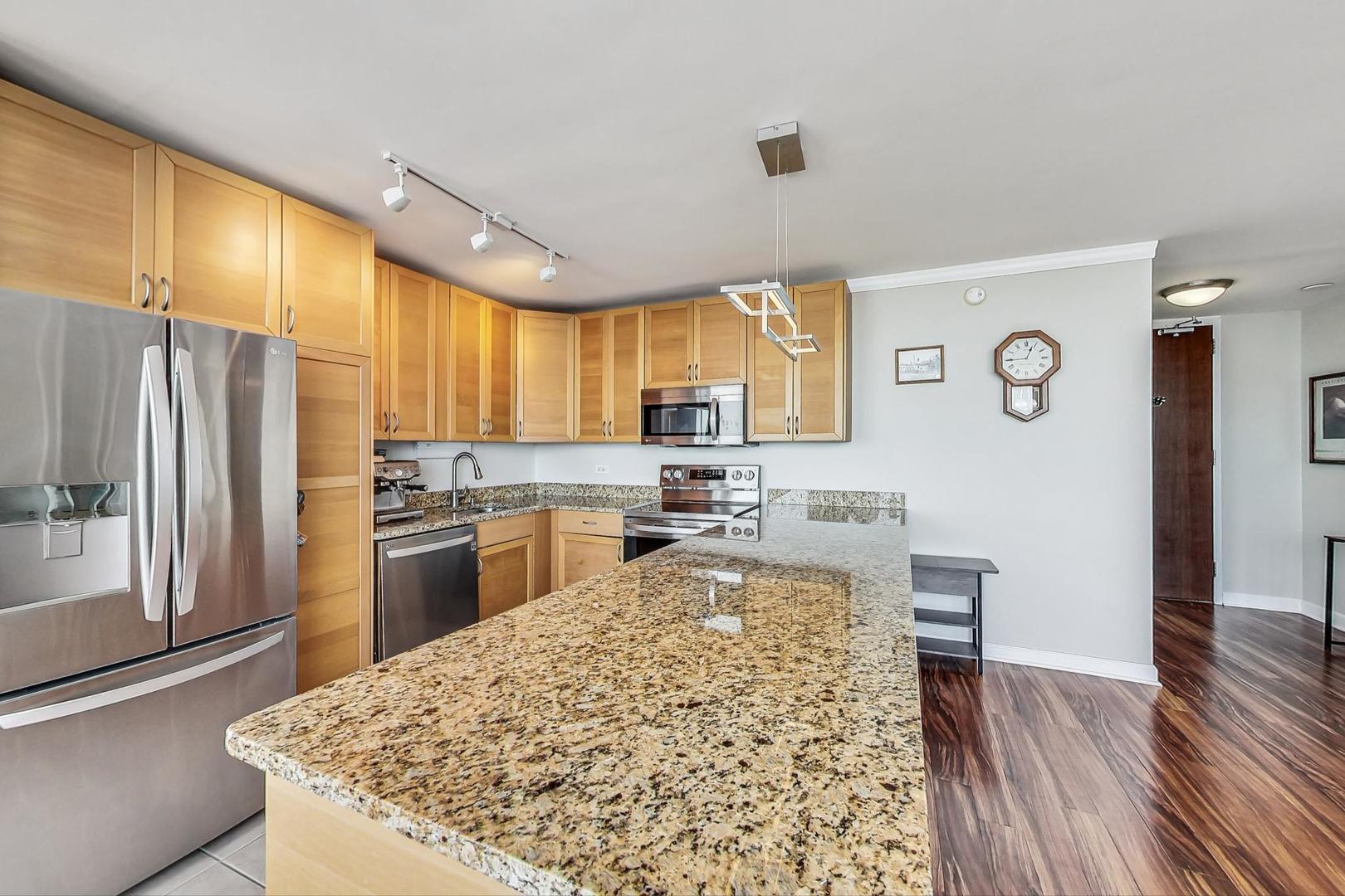 655 West Irving Park Road, Unit 5503 Chicago, IL 60613 - Photo 6 of 32 a kitchen with granite countertop a refrigerator cabinets and wooden floor