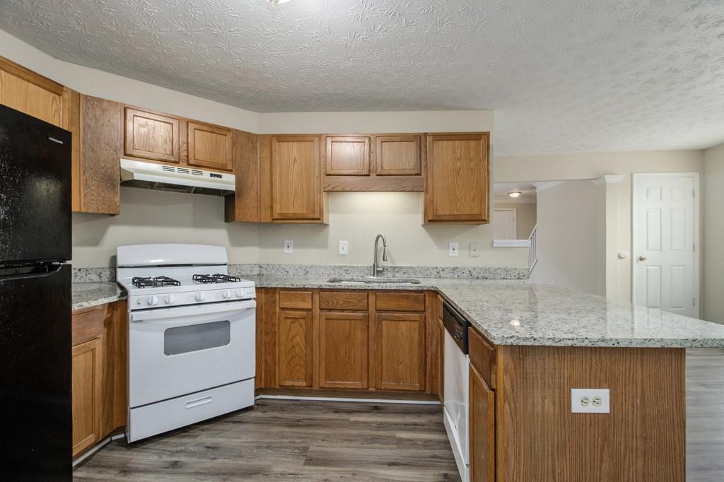 6510 Charter Way Lithonia, GA 30058 - Photo 11 of 27 a kitchen with stainless steel appliances granite countertop a stove a sink dishwasher and a refrigerator with wooden cabinets