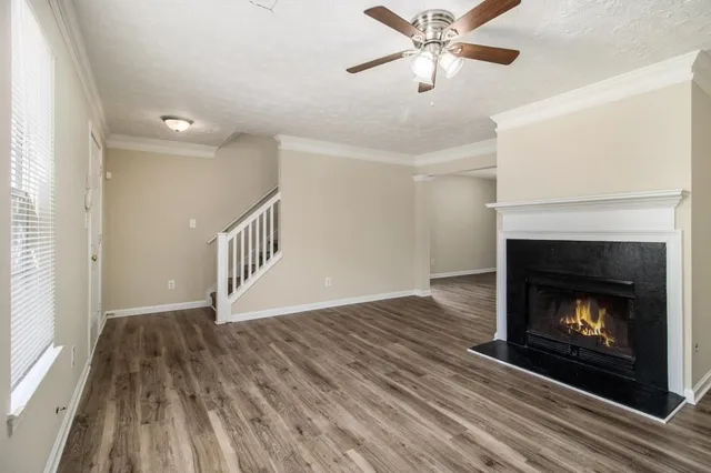 a view of an empty room with wooden floor fireplace and a window