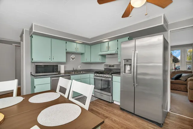 a kitchen with stainless steel appliances granite countertop a refrigerator a stove and a dining table with wooden floor