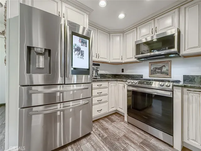 a kitchen with stainless steel appliances white cabinets and a stove top oven