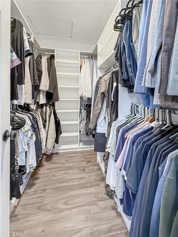 a view of walk in closet with clothes and shoes