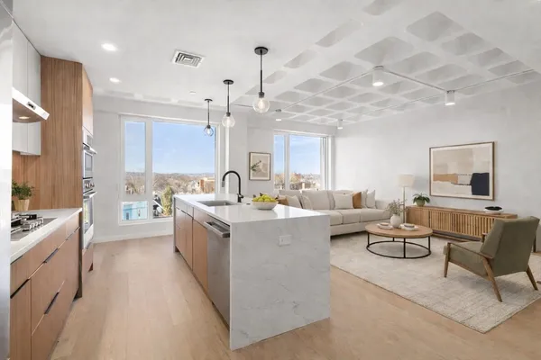 a large white kitchen with a stove a sink a couch and wooden floor