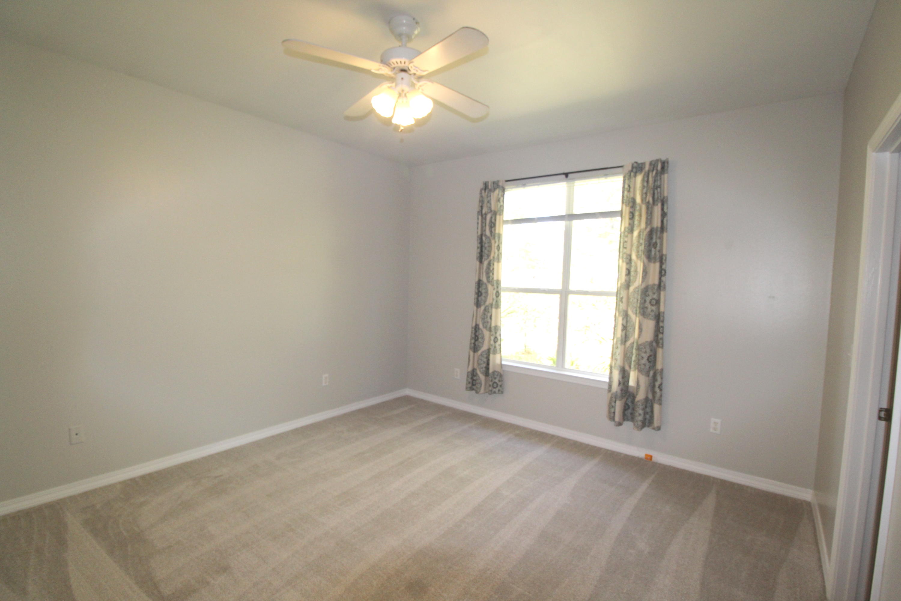 91 Walnut Street Santa Rosa Beach, FL 32459 - Photo 18 of 39 an empty room with chandelier fan and windows