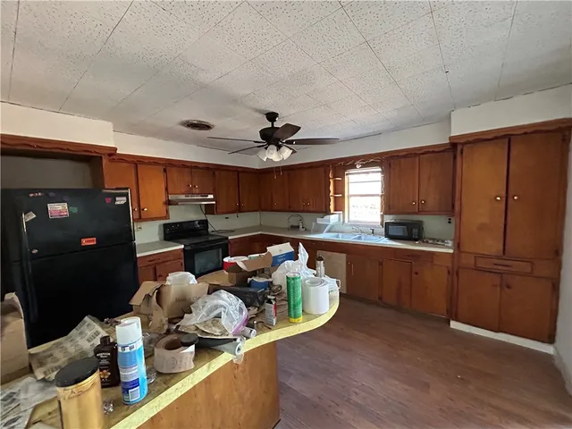 a kitchen with stainless steel appliances granite countertop a refrigerator a sink dishwasher a stove and a dining table with wooden floor