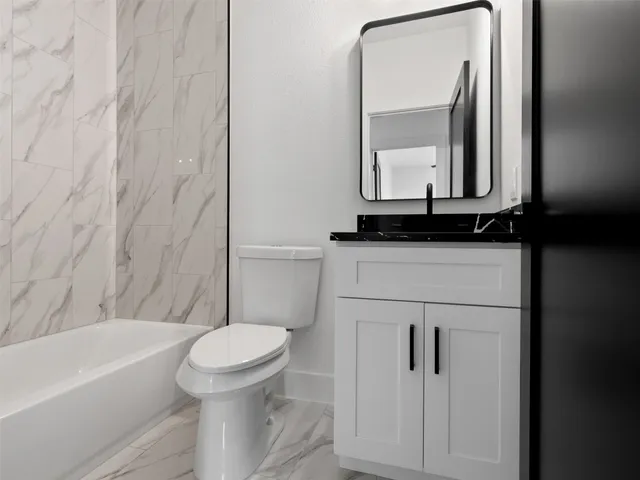a bathroom with a granite countertop toilet sink and mirror