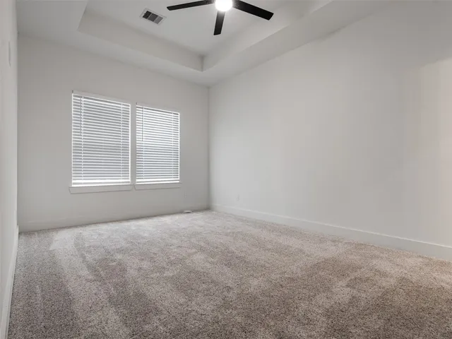 an empty room with a chandelier fan and windows