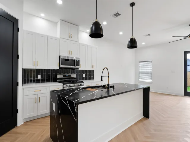 a kitchen with stainless steel appliances granite countertop a sink a stove and a refrigerator