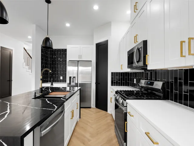 a kitchen with kitchen island granite countertop a sink stainless steel appliances and white cabinets