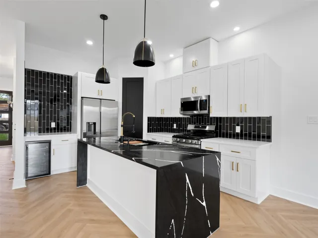 a kitchen with stainless steel appliances granite countertop a stove a sink and a microwave