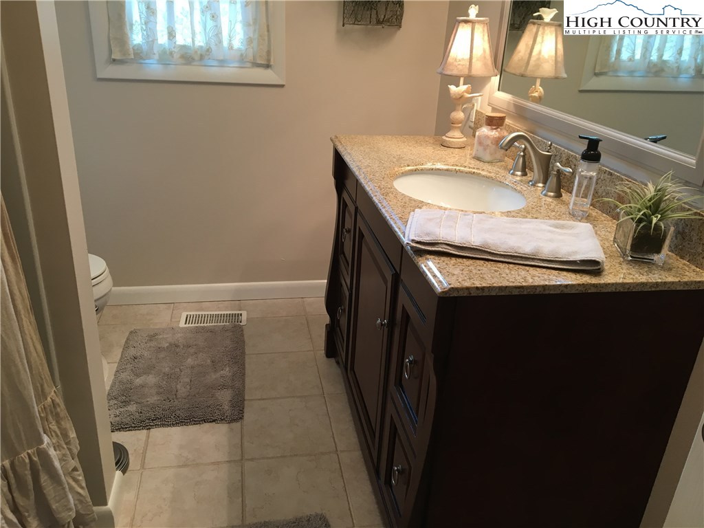 172 Deer Street Boone, NC 28607 - Photo 6 of 7 a bathroom with a granite countertop sink a mirror and a