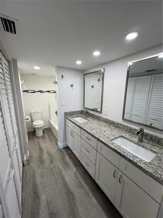 a spacious bathroom with a granite countertop sink a toilet and a large mirror