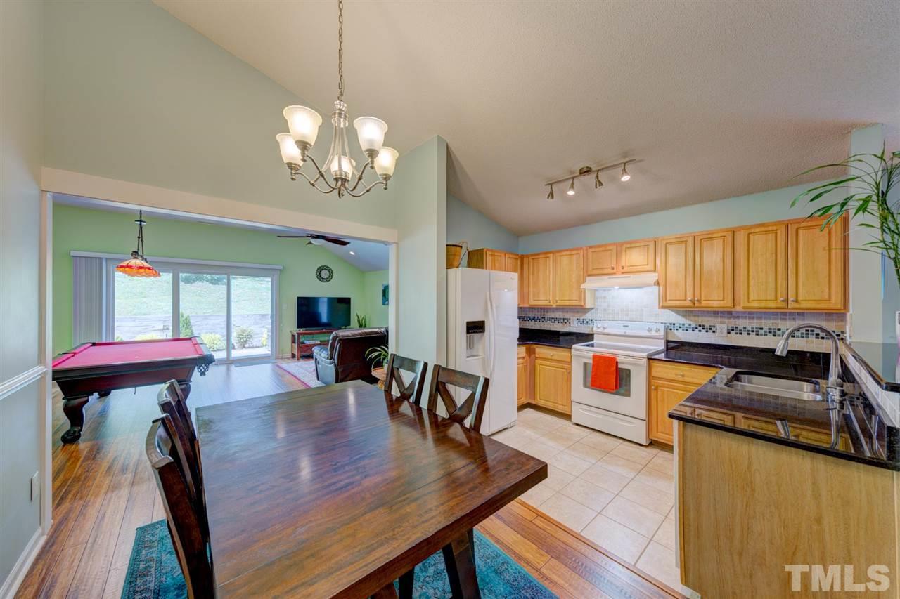 4845 Silverdene Street Raleigh, NC 27616 - Photo 4 of 24 a kitchen with stainless steel appliances granite countertop a stove top oven a dining table and chairs with wooden floor