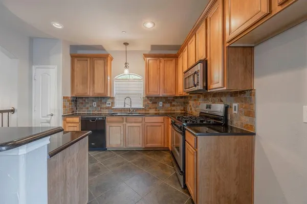 a kitchen with stainless steel appliances granite countertop a stove a sink and a refrigerator