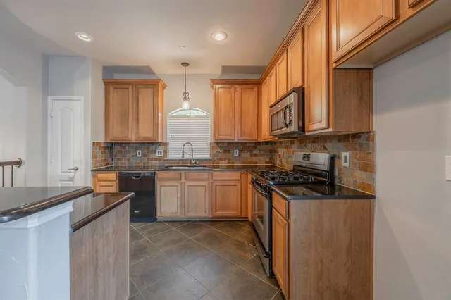 a kitchen with stainless steel appliances granite countertop a stove a sink and a refrigerator