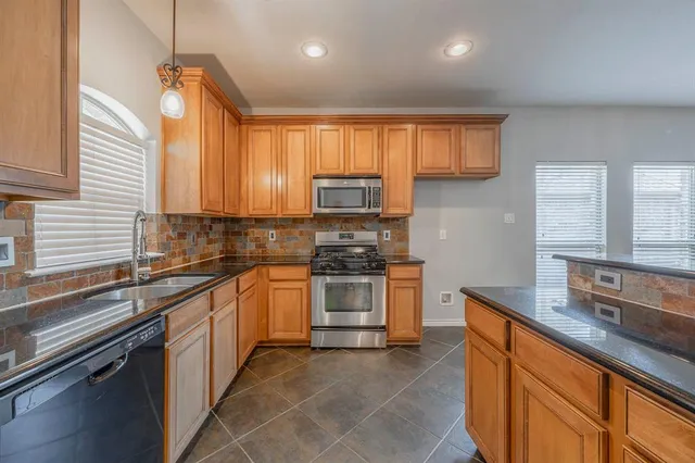 a kitchen with stainless steel appliances granite countertop a sink stove and microwave