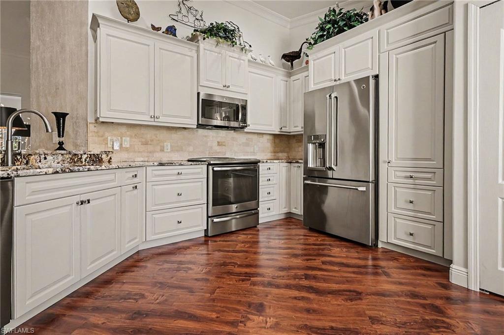 9341 Spring Run Boulevard, Unit 3108 Estero, FL 34135 - Photo 11 of 30 Kitchen with stainless steel appliances, white cabinets, and ornamental molding