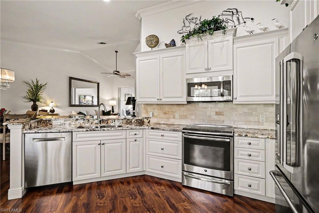 9341 Spring Run Boulevard, Unit 3108 Estero, FL 34135 - Photo 12 of 30 Kitchen with stainless steel appliances, white cabinetry, lofted ceiling, light stone countertops, and a peninsula