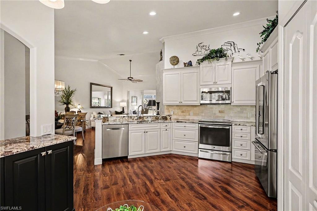 9341 Spring Run Boulevard, Unit 3108 Estero, FL 34135 - Photo 10 of 30 Kitchen featuring appliances with stainless steel finishes, vaulted ceiling, light stone counters, white cabinetry, and crown molding