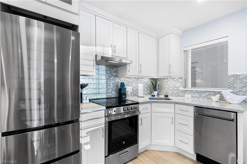 175 5th Avenue South, Unit 3 Naples, FL 34102 - Photo 7 of 31 a kitchen with stainless steel appliances granite countertop a refrigerator sink and cabinets