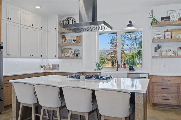 a kitchen with stainless steel appliances granite countertop a table chairs in it and wooden floors