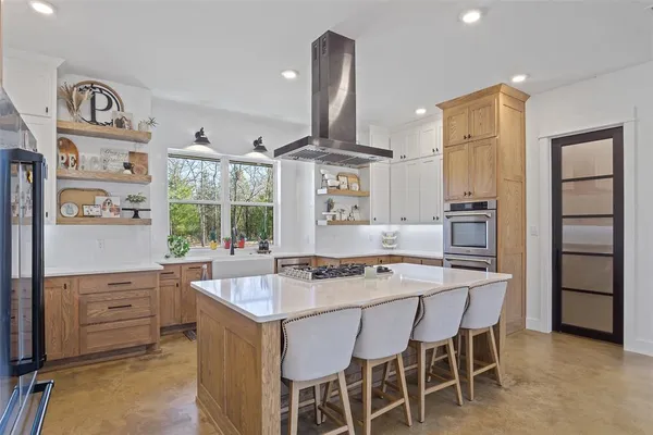 a kitchen with stainless steel appliances kitchen island granite countertop a table chairs in it and wooden floors