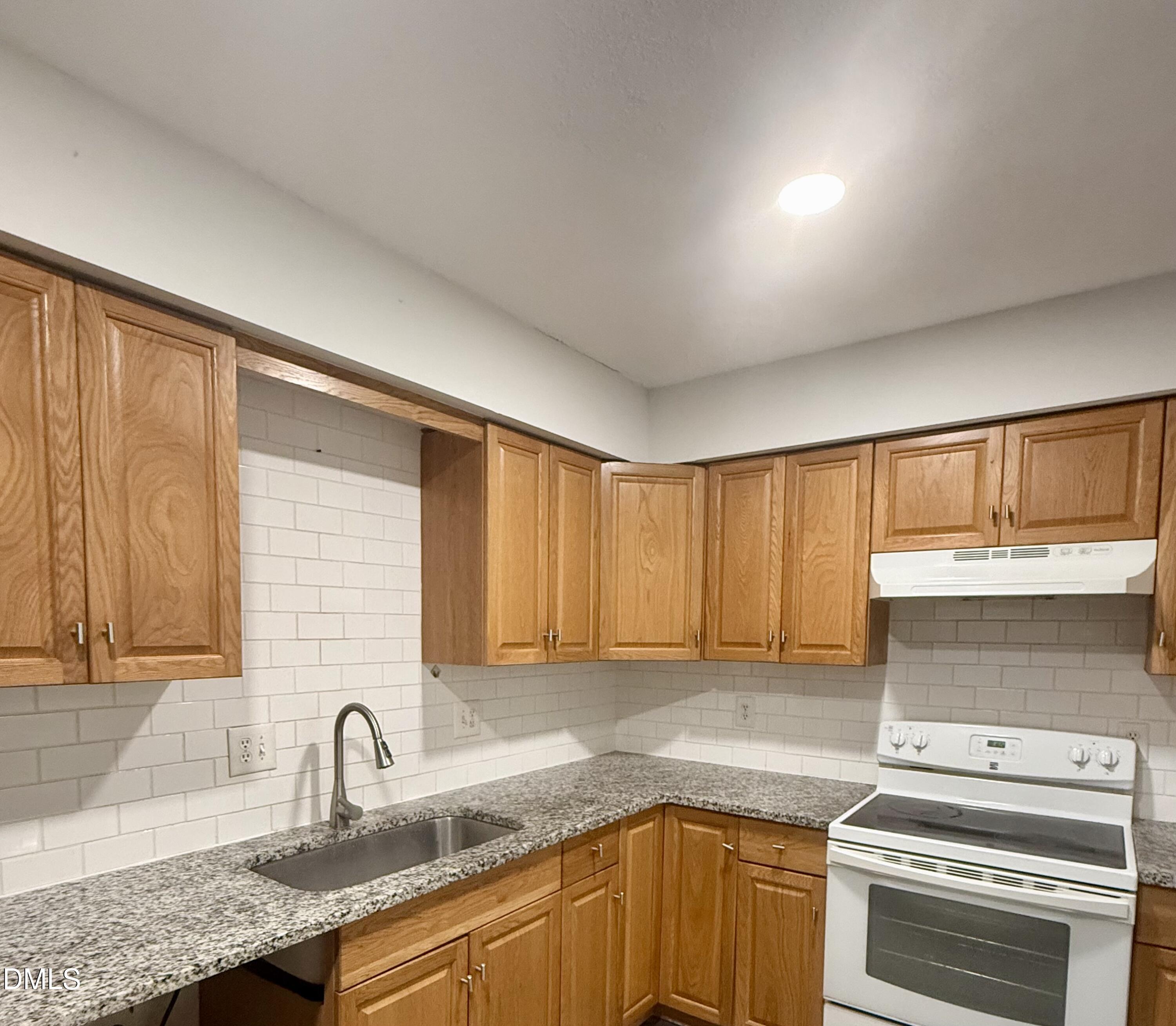 546 Pine Ridge Place Raleigh, NC 27609 - Photo 7 of 28 a kitchen with granite countertop a sink a stove and cabinets