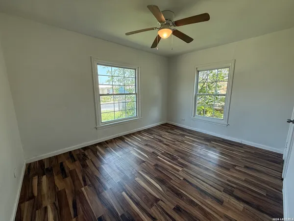 a view of empty room with wooden floor and fan