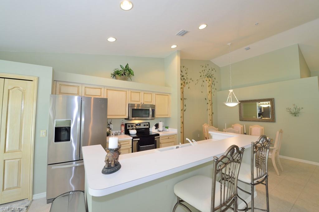 21370 Lancaster Run, Unit 1622 Estero, FL 33928 - Photo 8 of 28 a kitchen with stainless steel appliances granite countertop a refrigerator a stove a sink a dining table and chairs with wooden floor