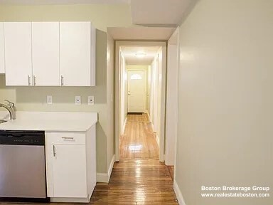 4043 Washington Street, Unit 2 Boston, MA 02131 - Photo 3 of 8 a view of a kitchen with white cabinets and wooden floor