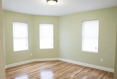 4043 Washington Street, Unit 2 Boston, MA 02131 - Photo 5 of 8 a view of an empty room with wooden floor and a window