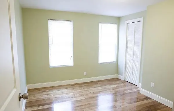 a view of empty room with wooden floor and fan