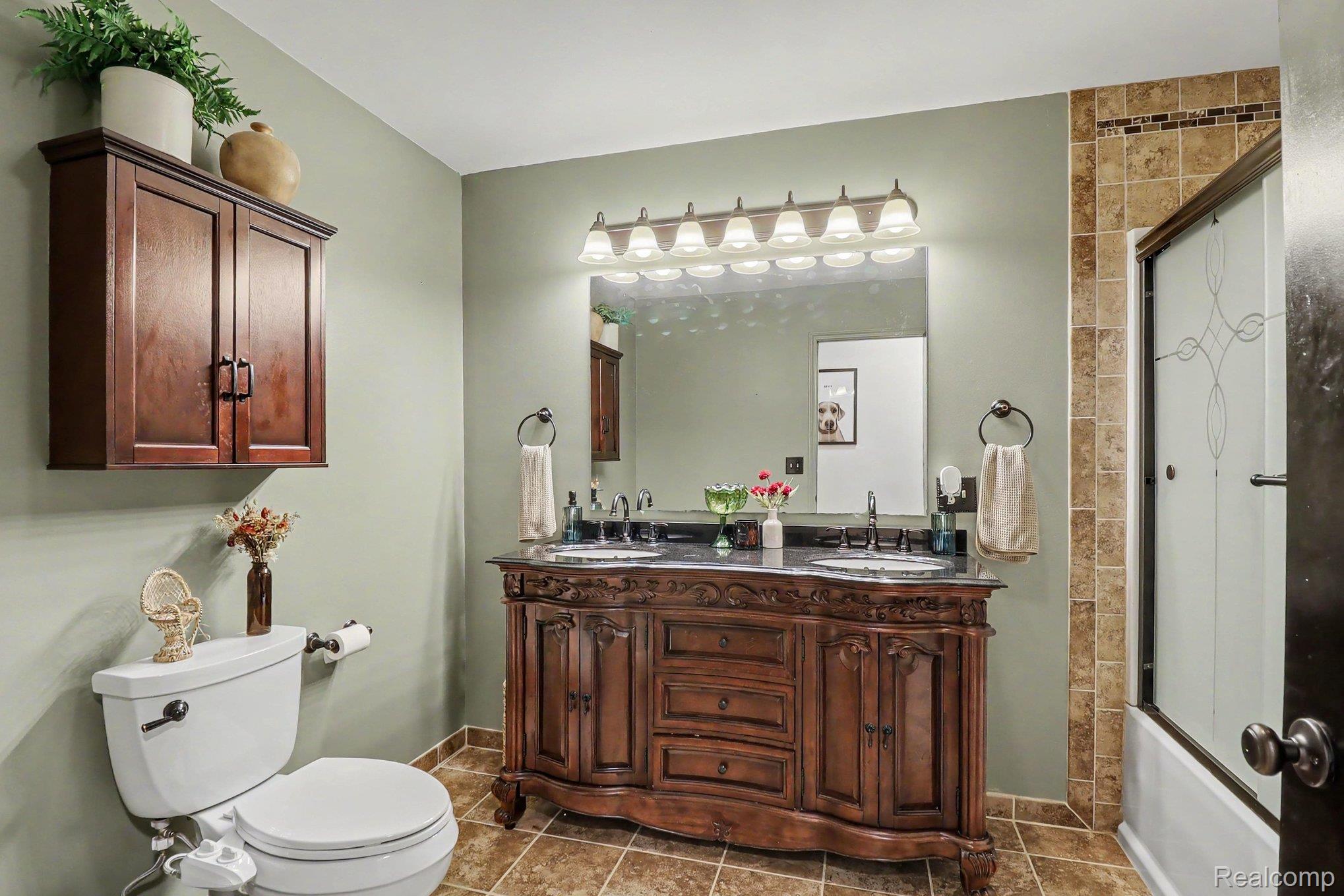 2905 German Road Columbiaville, MI 48421 - Photo 20 of 31 Double vanity with dark wood cabinetry and integrated sinks, complemented by a large framed mirror with overhead vanity lighting