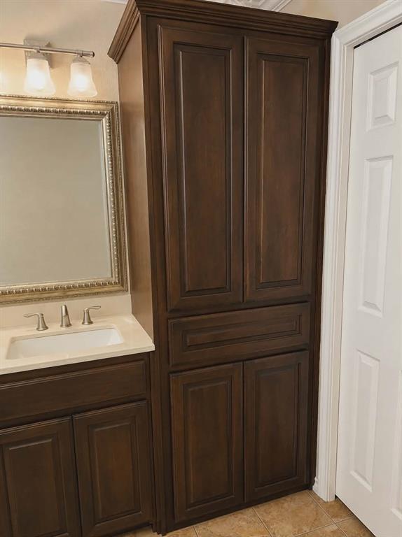 14752 Ranch Road Forney, TX 75126 - Photo 19 of 40 Bathroom cabinet featuring dark wood-finish cabinetry, a light-toned countertop, and an undermount sink-This photo was taken before family moved in