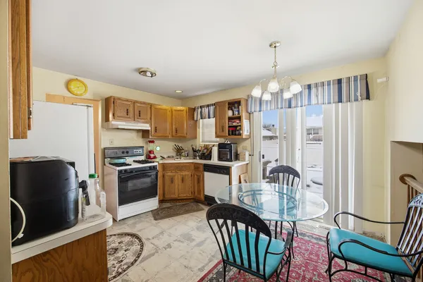 a kitchen with stainless steel appliances granite countertop a sink a stove a refrigerator a dining table and chairs