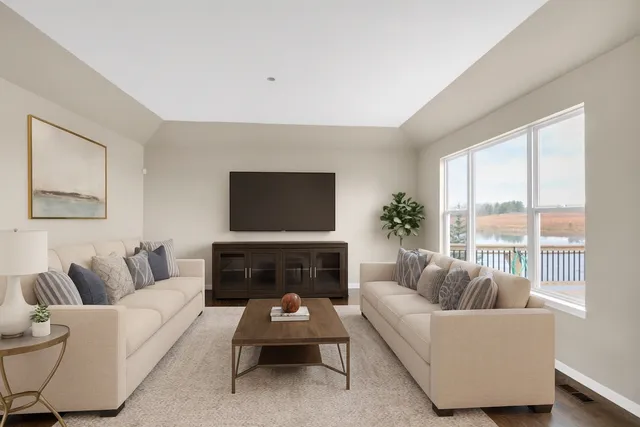 an empty room with wooden floor and kitchen view