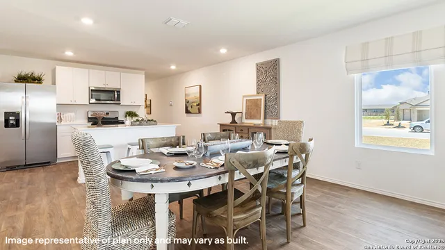 a dining room with stainless steel appliances kitchen island granite countertop a dining table chairs and a refrigerator