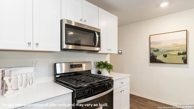 a kitchen with stainless steel appliances granite countertop white cabinets a stove top oven with wooden floor