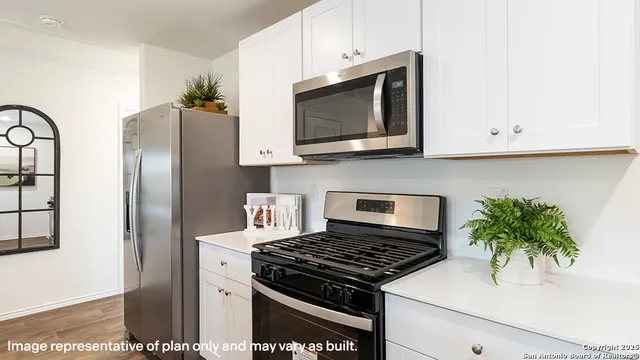 a kitchen with stainless steel appliances a microwave a stove and white cabinets