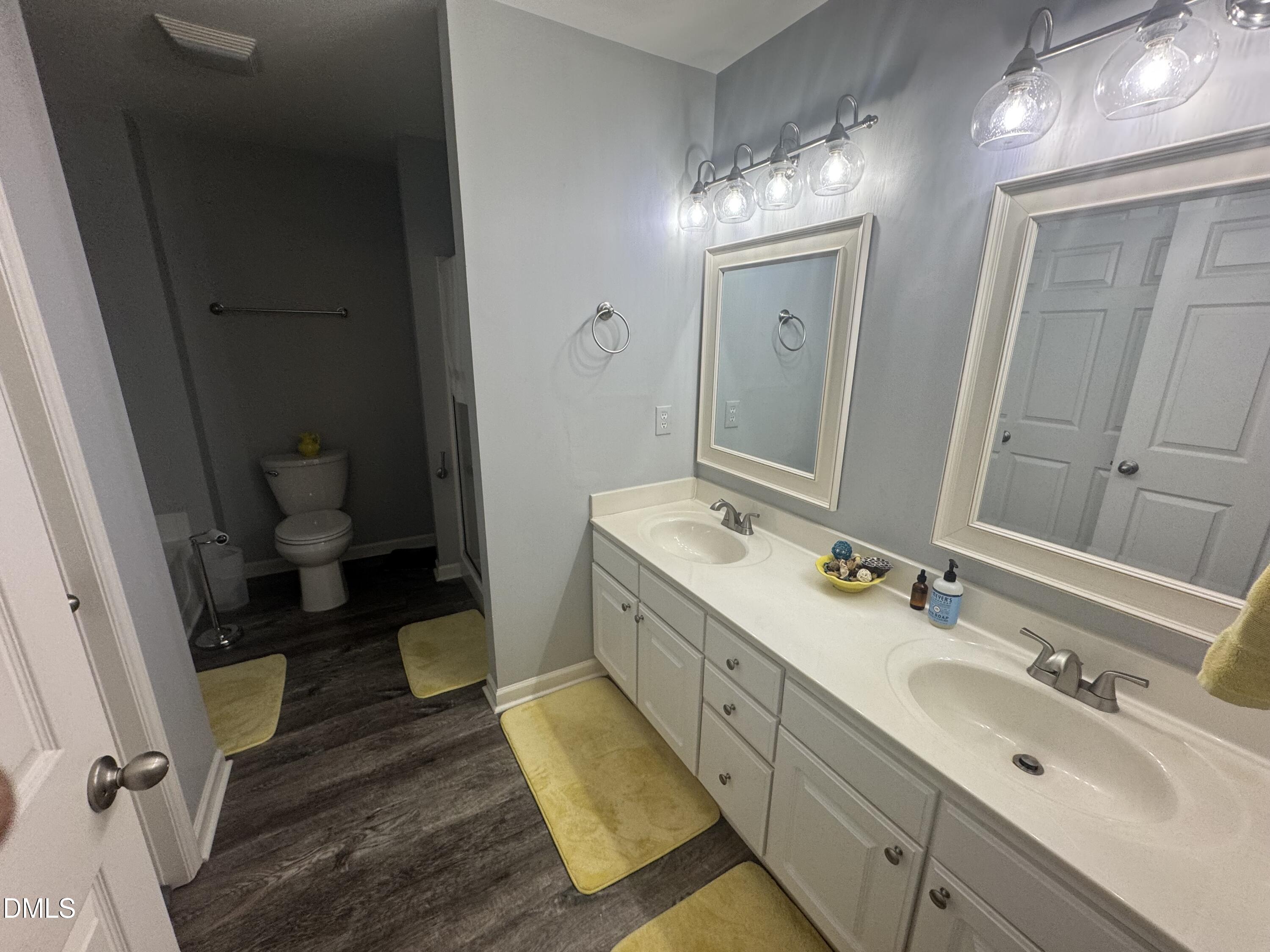 11351 Clubhaven Place, Unit 100 Raleigh, NC 27617 - Photo 20 of 29 a bathroom with a double vanity sink and mirror with toilet