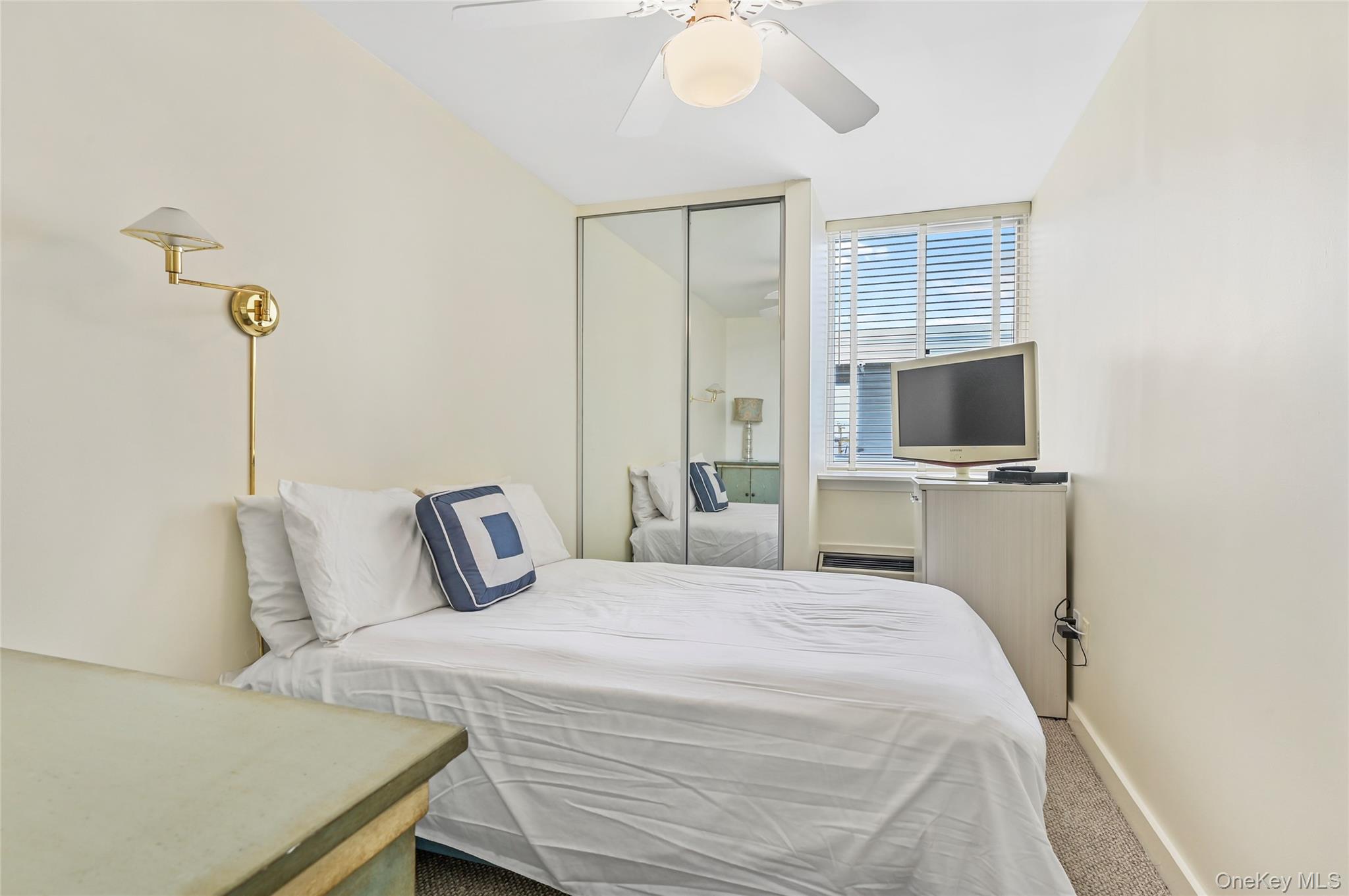 265 Dune Road, Unit 68 Westhampton Beach, NY 11978 - Photo 17 of 25 a bedroom with a bed and a flat tv screen on dresser