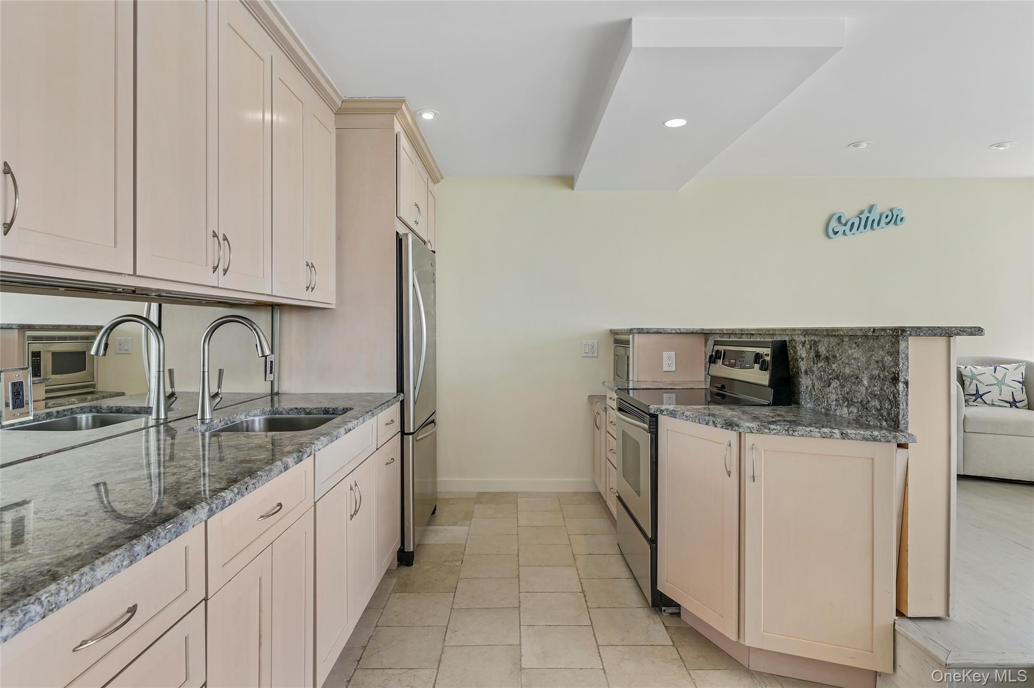 265 Dune Road, Unit 68 Westhampton Beach, NY 11978 - Photo 4 of 25 a kitchen with granite countertop a sink and white cabinets