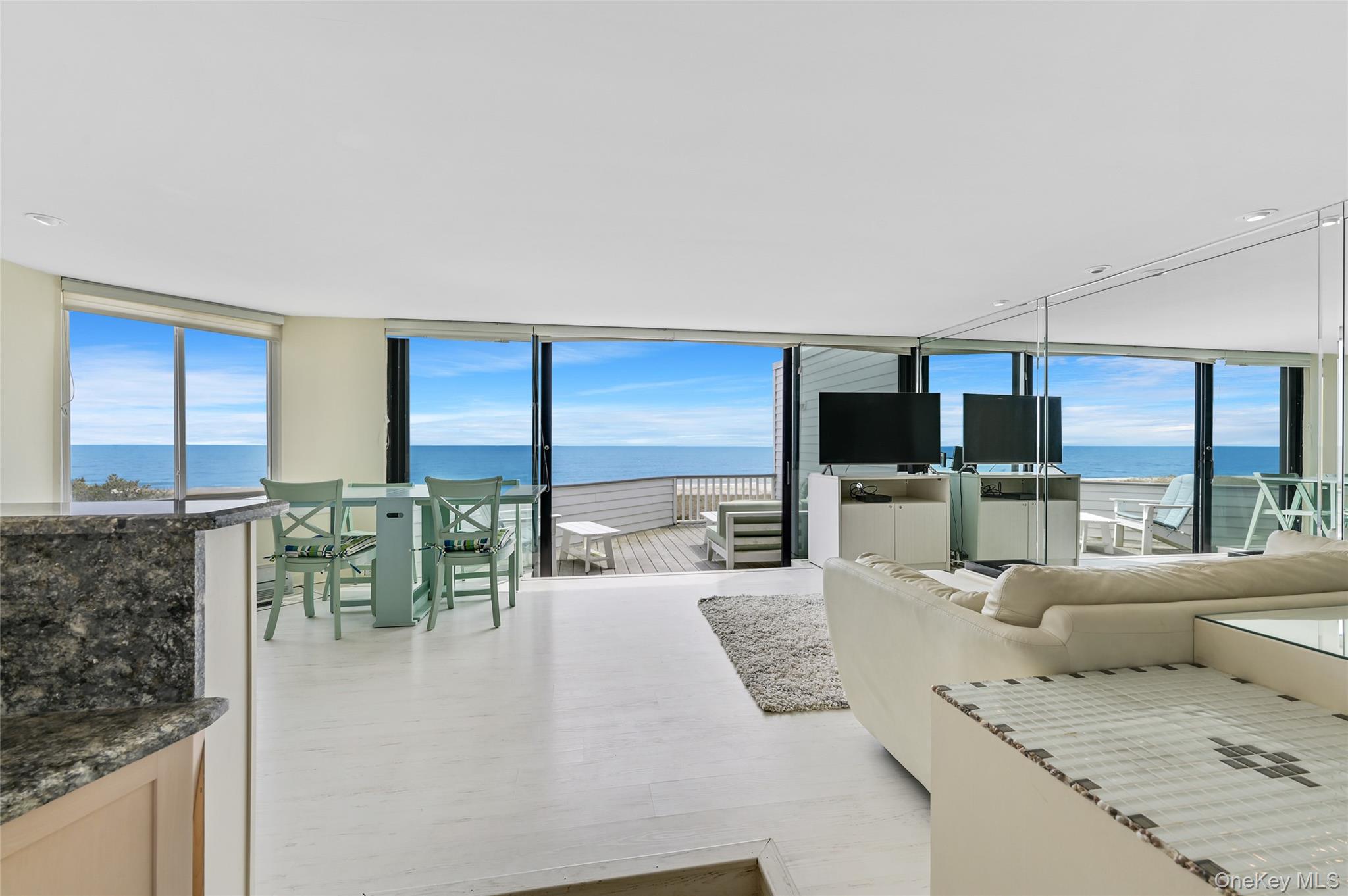 265 Dune Road, Unit 68 Westhampton Beach, NY 11978 - Photo 7 of 25 a living room with furniture and a flat screen tv