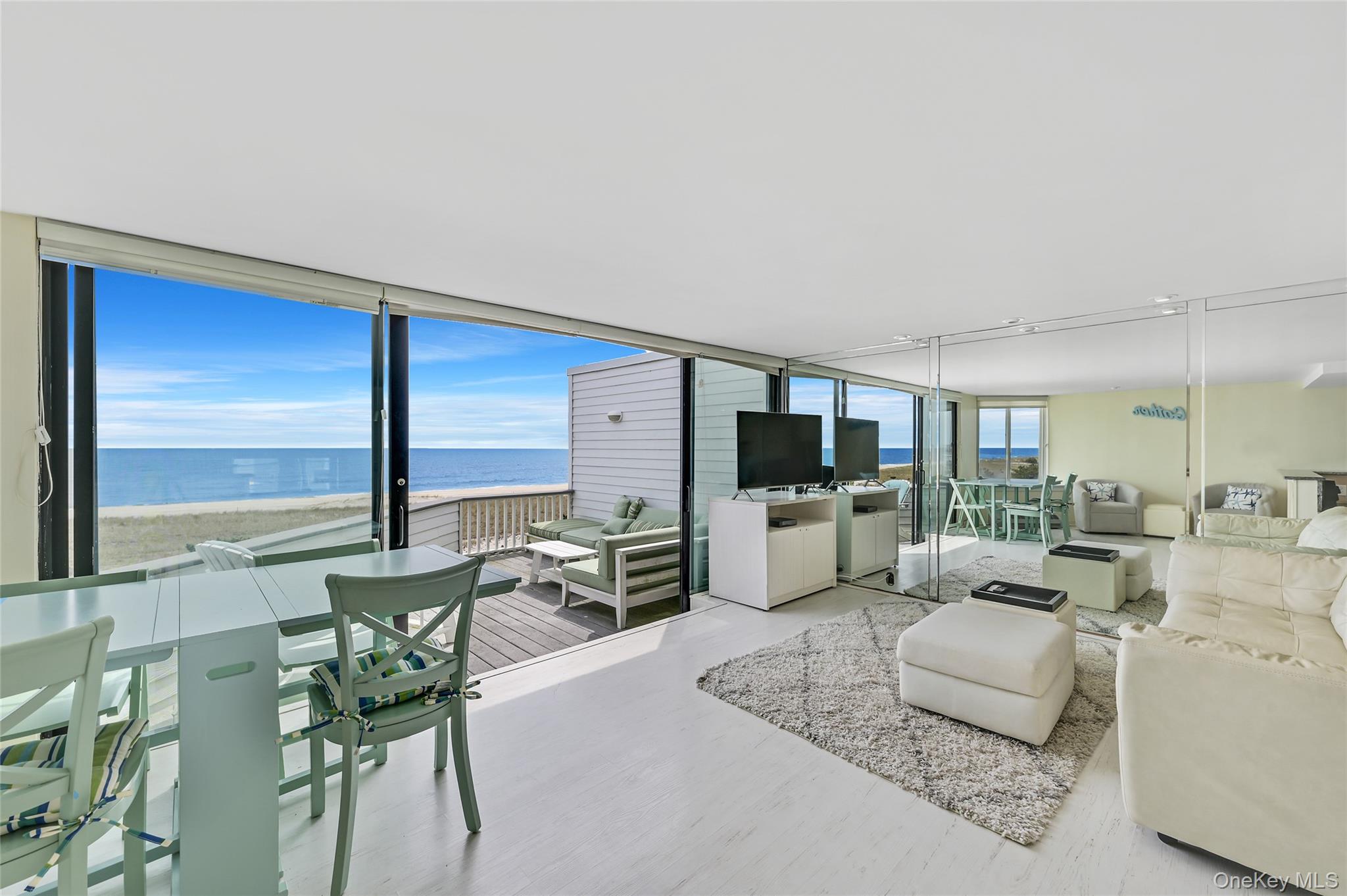 265 Dune Road, Unit 68 Westhampton Beach, NY 11978 - Photo 9 of 25 a living room with furniture a flat screen tv and a large window