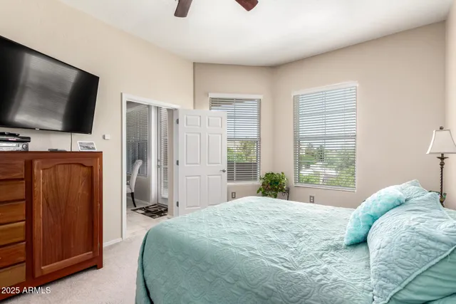 a bedroom with a bed flat screen tv and a large window
